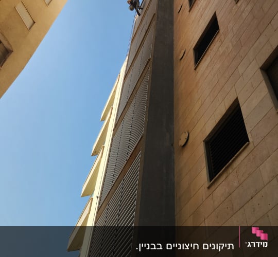 אדם מבצע עבודות בגובה על בניין גבוה